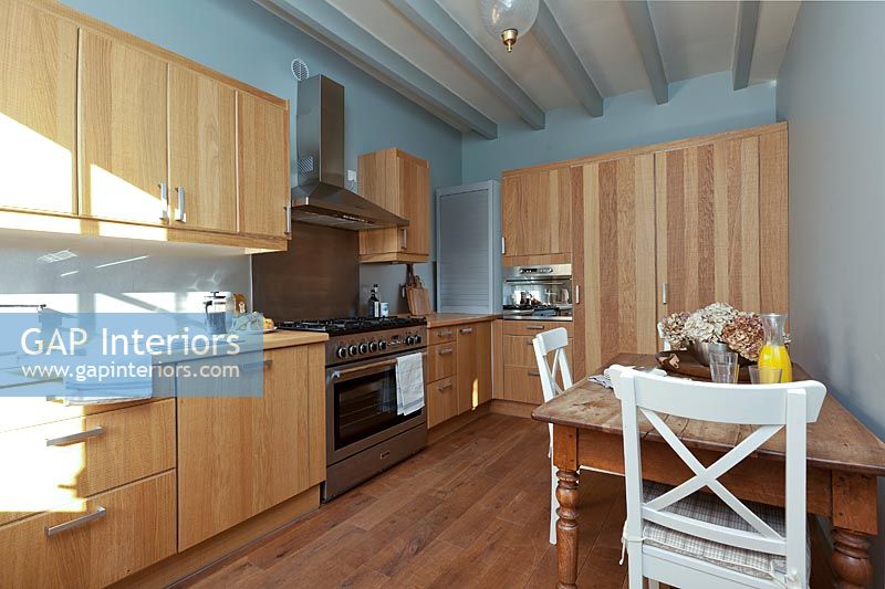 Modern wooden kitchen-diner with pale blue painted walls 