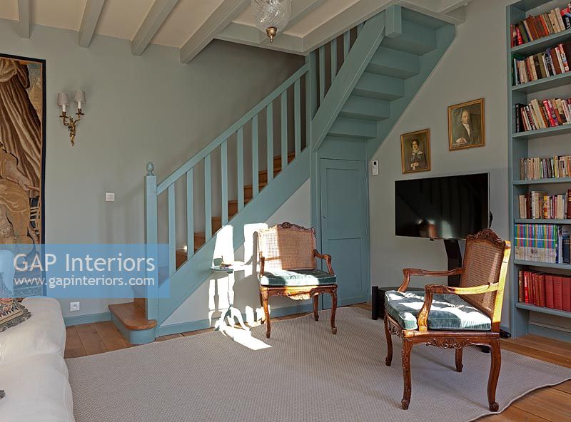 Blue painted staircase and matching bookcase in country living room 