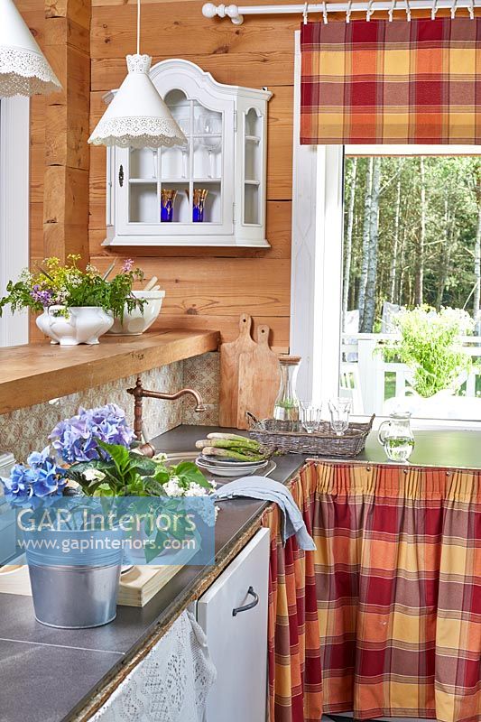 Country kitchen with checked fabric skirts on cupboards 