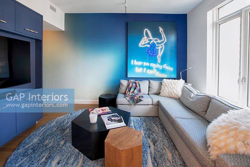 Modern living room with neon artwork on blue painted wall 