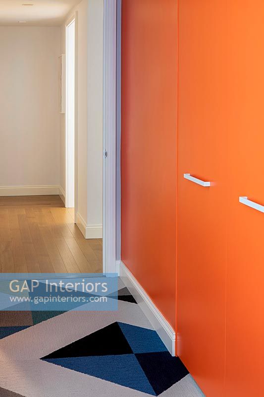 Bright orange painted wardrobe doors and patterned carpet