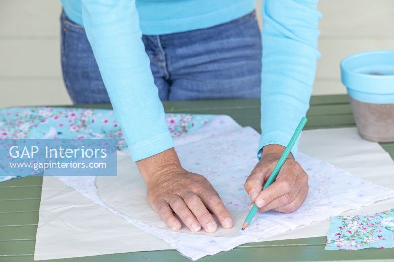 Using a pencil to mark around the template on a sheet of fabric