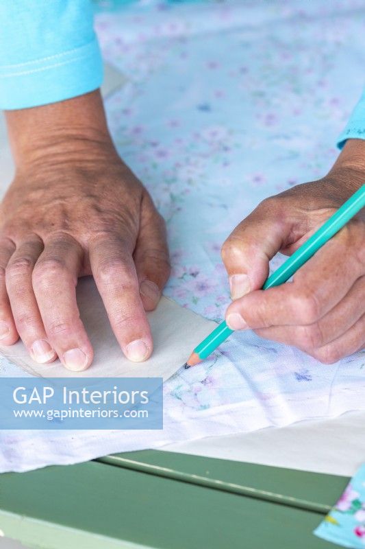 Using a pencil to mark around the template on a sheet of fabric