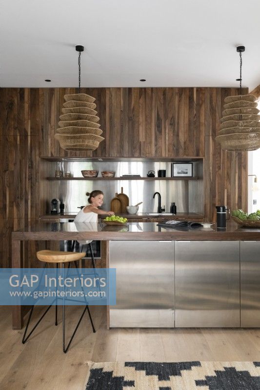 Girl in an open-plan modern kitchen with built-in cabinet in wood and stainless steel
