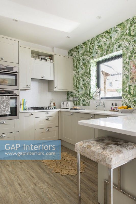 Tropical patterned wall paper on feature wall of modern kitchen 