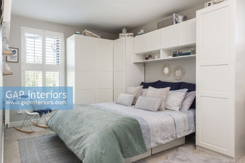 Built-in wardrobes and units around bed in modern bedroom 