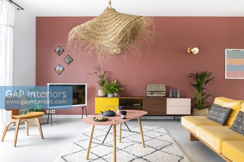 Modern living room with pink feature wall and yellow furniture 