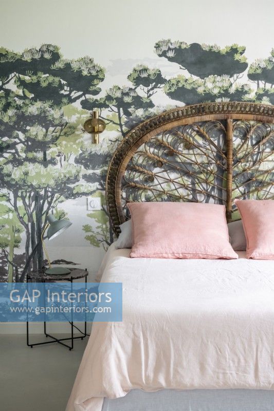Mural feature wall behind bed with decorative wicker headboard 