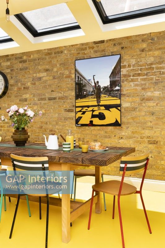 Modern dining area with exposed brick, yellow rubber floor, upcycled table and chairs