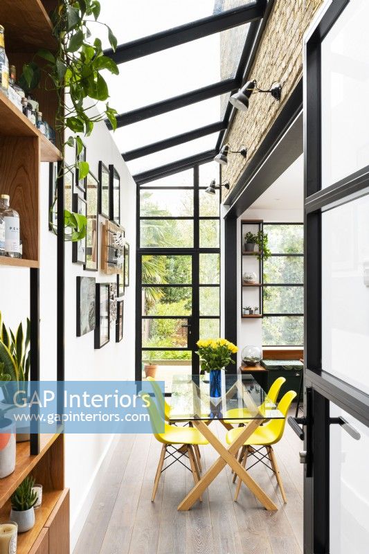 Contemporary kitchen extension, side return, with crittall windows and yellow dining chairs.