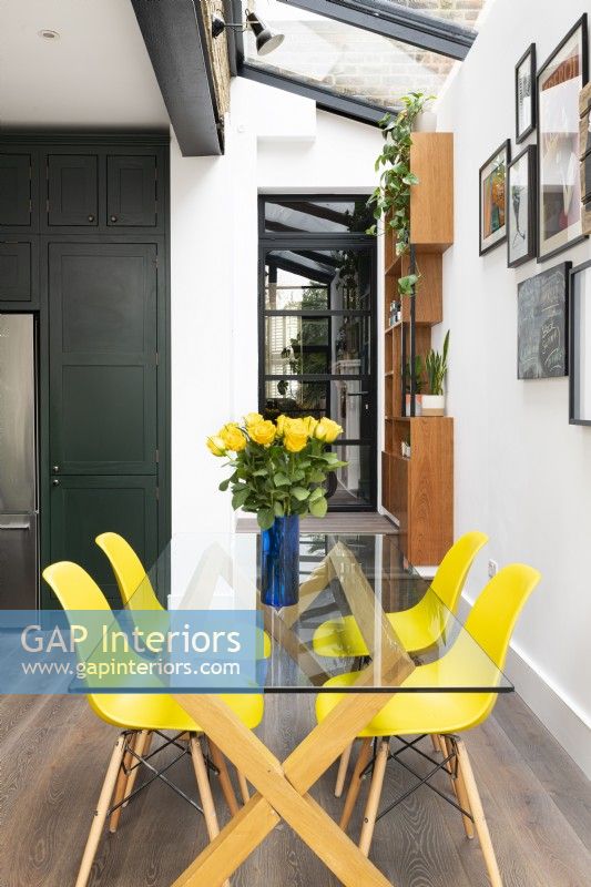 Contemporary kitchen extension, side return with glass dining table and yellow chairs