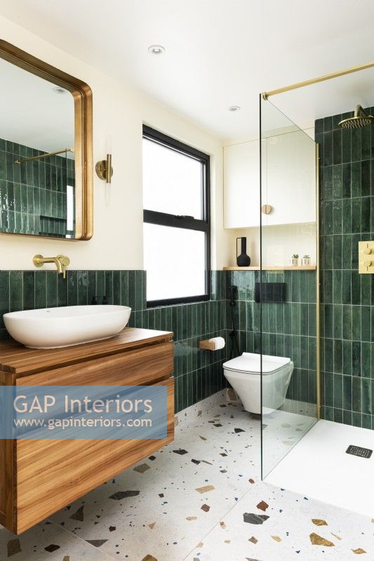 Contemporary modern bathroom with green vertical tiles, terrazzo floor tiles and brass fittings, taps