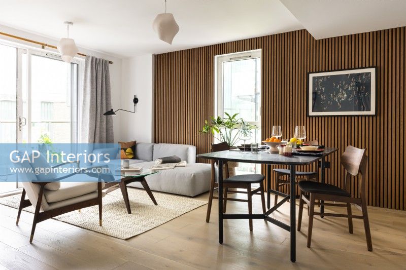 Open plan contemporary modern Japandi style living room with dining table and a slatted wall