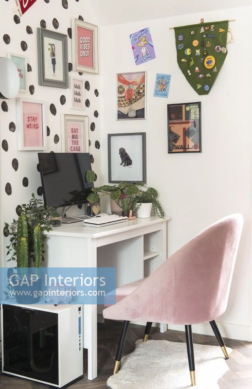 Modern desk and chair with colourful display of artwork on wall