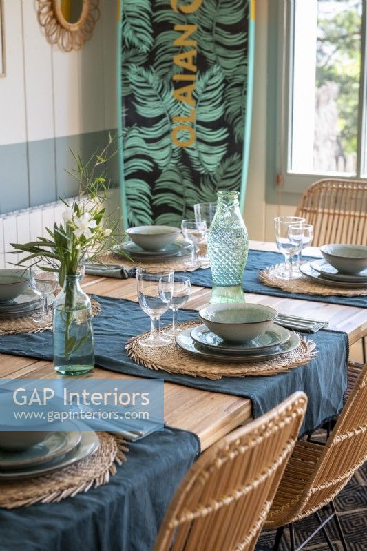 Detail of laid dining table with surf board in coastal cabin