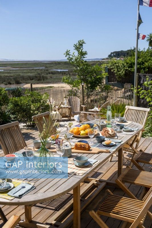 Outdoor dining table laid for lunch with coastal view in summer