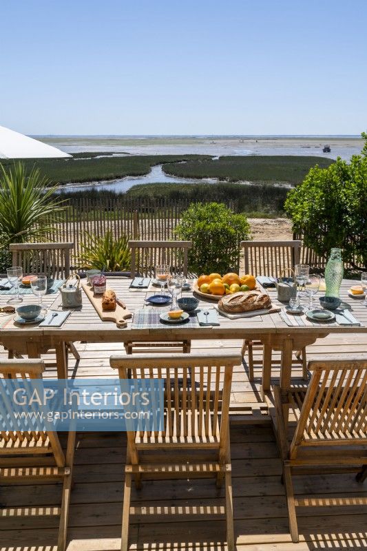 Outdoor dining table laid for lunch with coastal views in summer