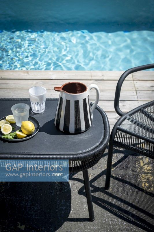 Water jug on black table next to swimming pool - detail