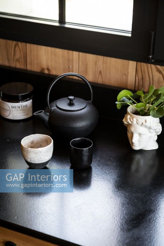 Tea pot and accessories on modern black kitchen worktop