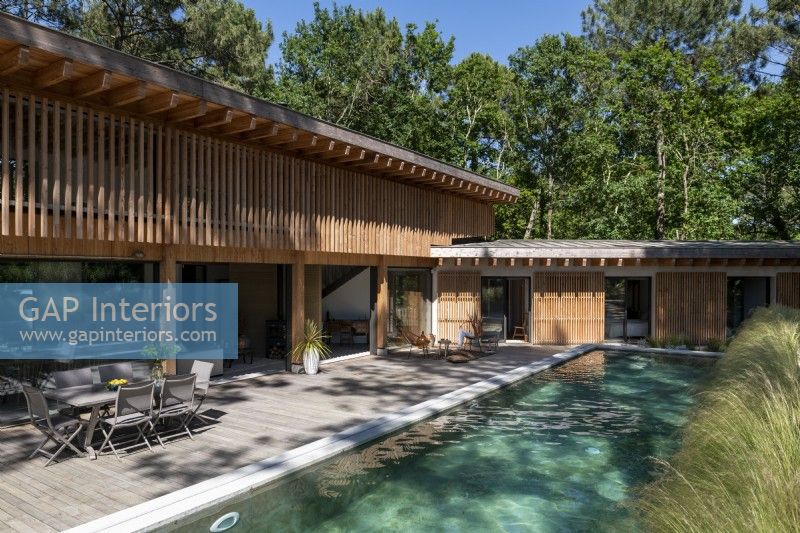Narrow natural pool outside contemporary wooden home