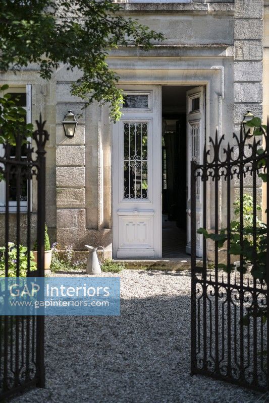 Wrought iron gates open to front door of large country house 
