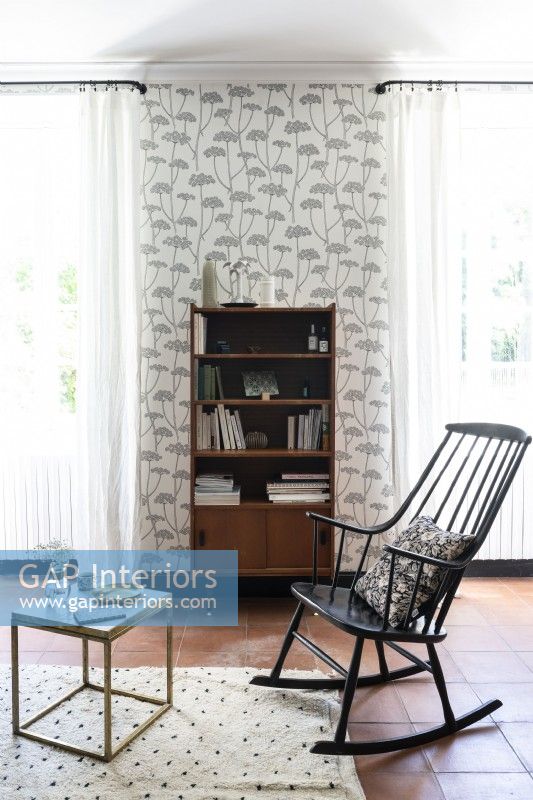 Black wooden rocking chair in living room with grey wallpaper