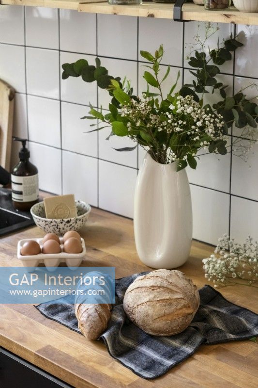Flower arrangement and fresh bread on kitchen worktop