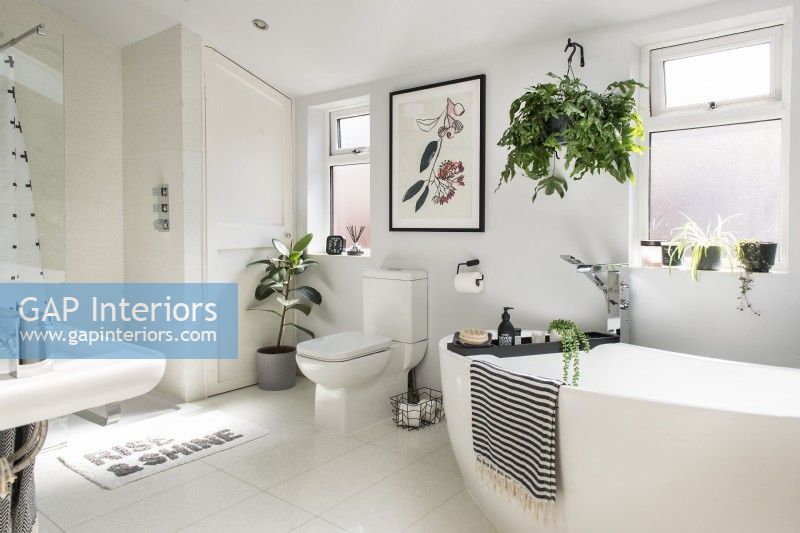 Modern bathroom with artwork on wall and lots of houseplants 