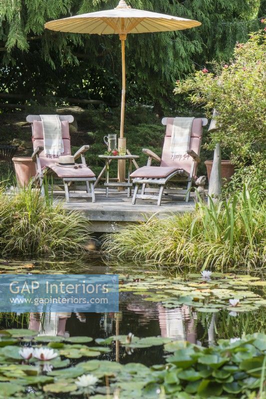 Recliners and parasol next to natural pond