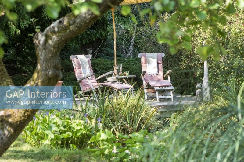 Recliners next to pond in country garden