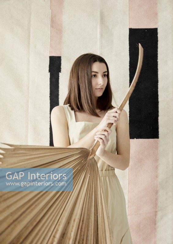 Woman holding large dried palm leaf 