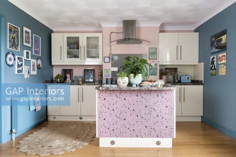 View into modern kitchen with white units and blue and pink walls