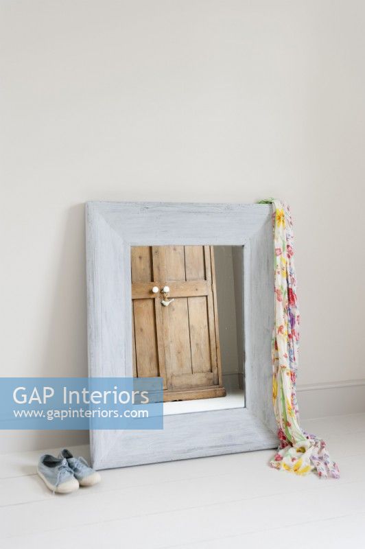Distressed framed mirror leaning against a wall
