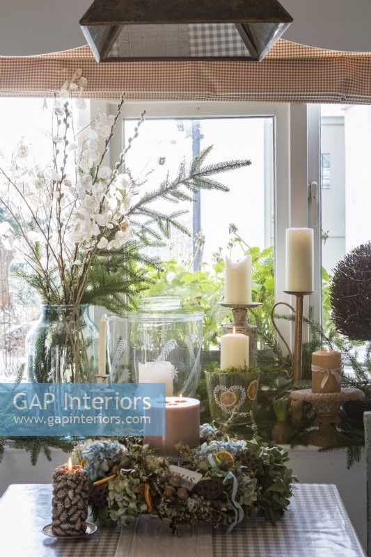 Candles and christmas evergreen foliage in cosy cottage