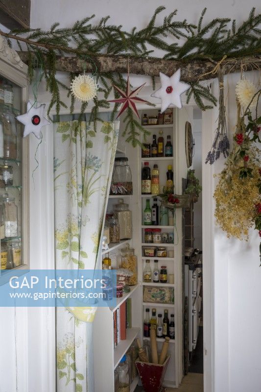 Decorative christmas foliage and baubles hanging in front of kitchen pantry