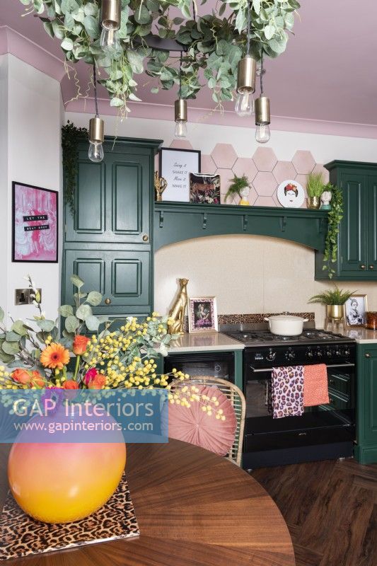 Kitchen with range and green painted cabinets and pink ceiling
