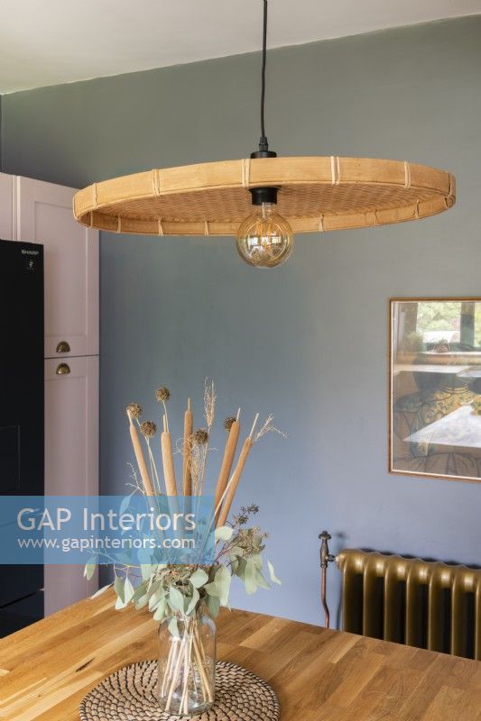 Pendant lamp with wicker shade hanging over a kitchen worktop