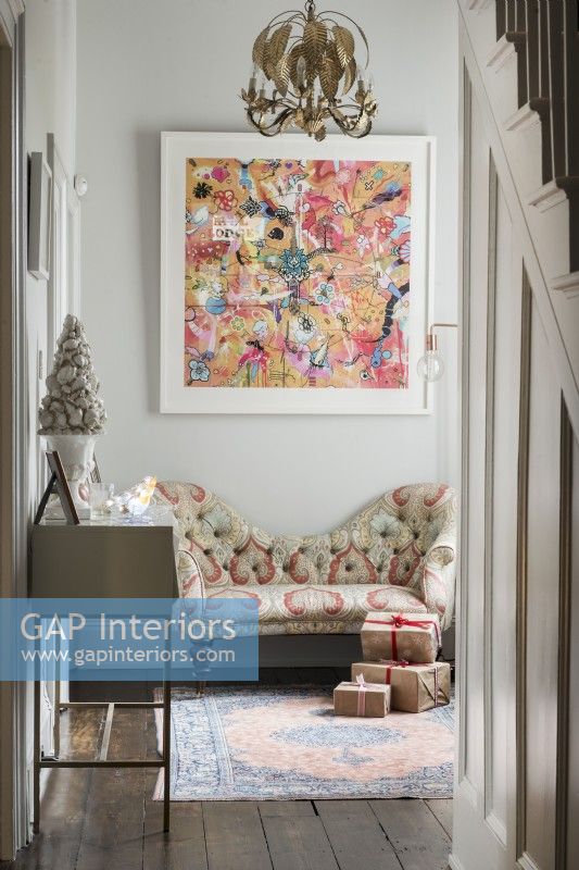 Large colourful artwork above love seat sofa in hallway