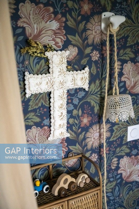 Decorative fabric cross on wallpapered wall - detail
