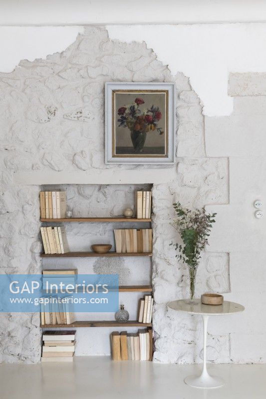 Bookshelves in alcove of white painted stone wall