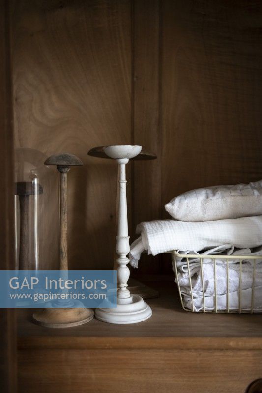 Basket of linen and old candlesticks on wooden unit - detail