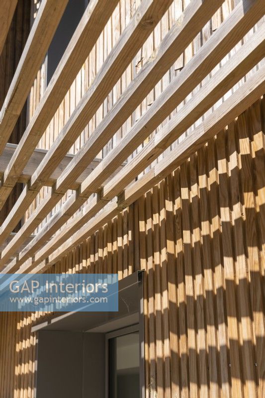 Detail of slatted wooden awning on modern timber clad house