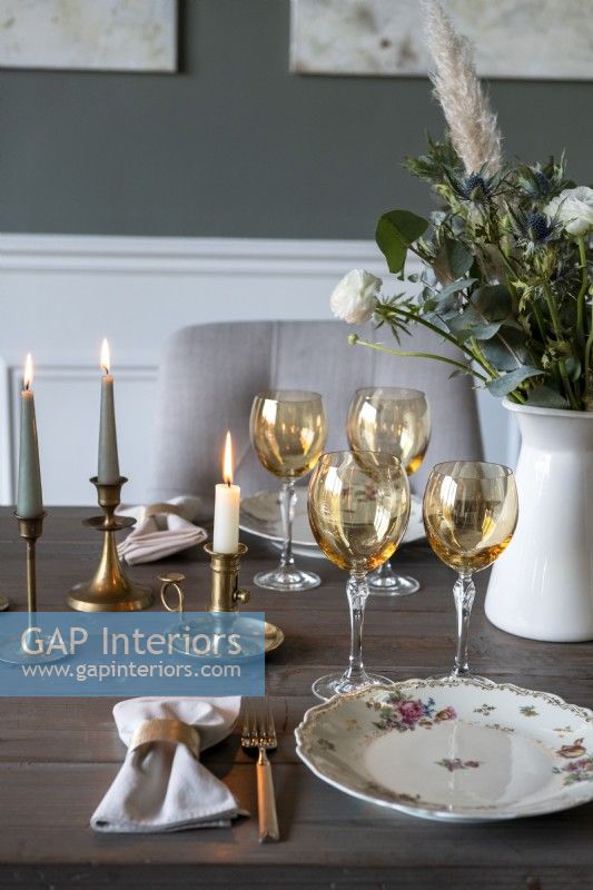 Gold glasses on dining room table with candles