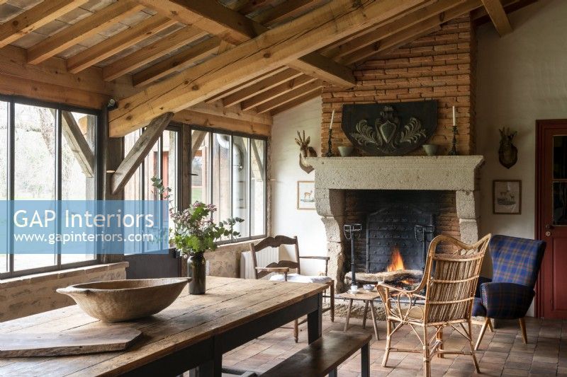 Rustic wooden table in country dining room with lit fireplace