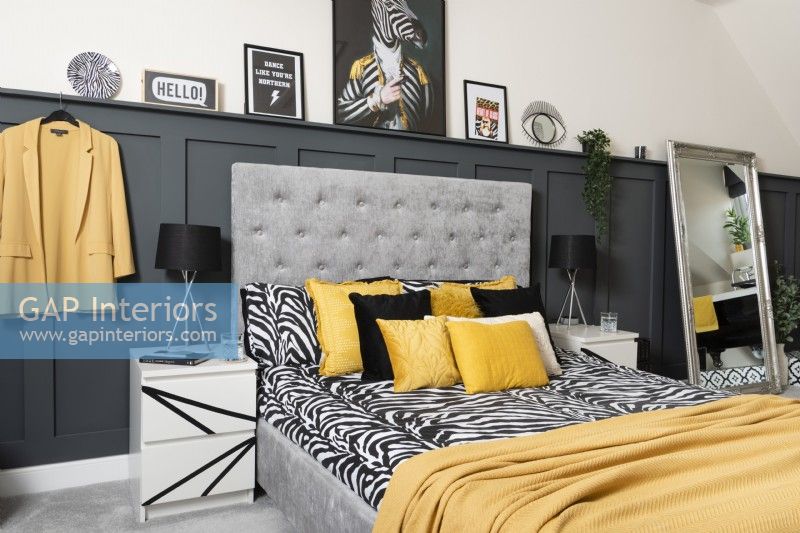 A monochrome and yellow bedroom with grey panelling
