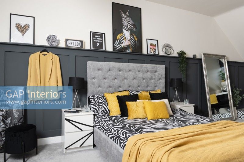 A monochrome and yellow bedroom with grey panelling
