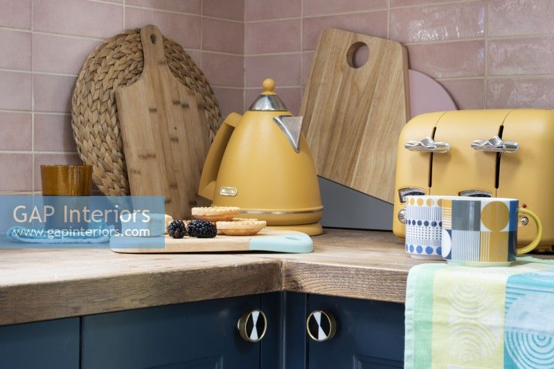 Detail of kitchen corner and worktop with kettle, toaster and chopping boards
