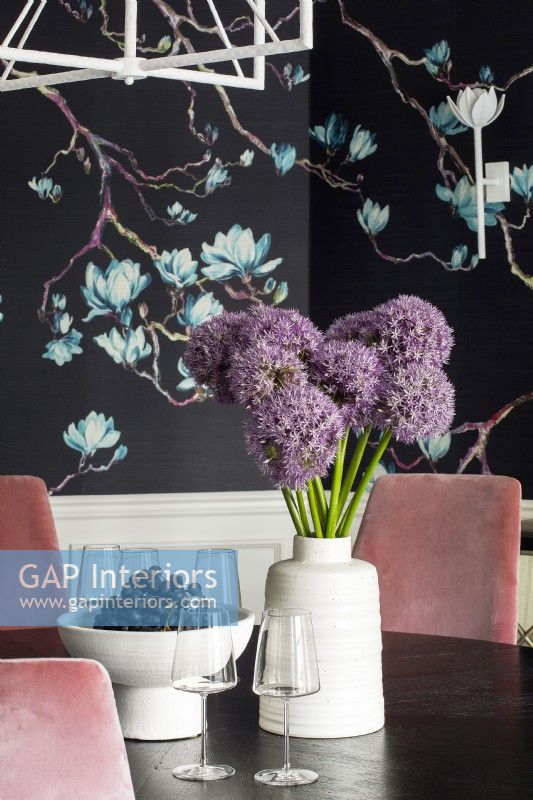 Details of purple flowers and grapes on dining room table and floral wallpaper.