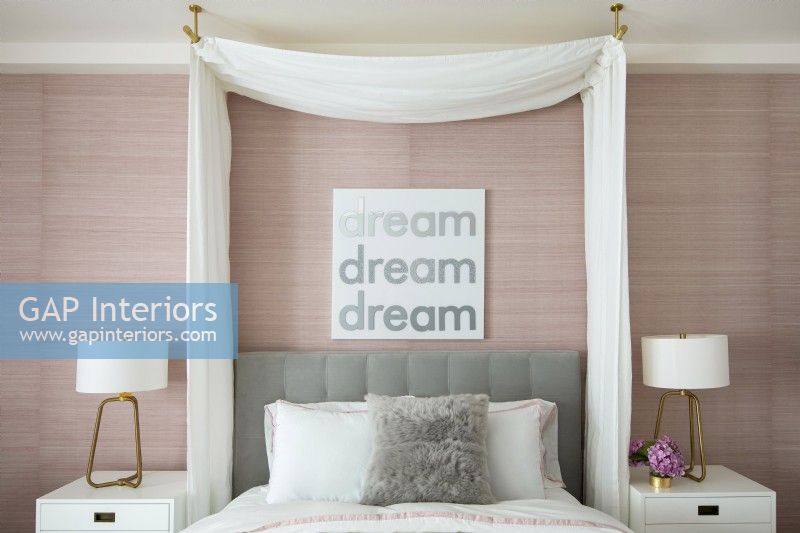Feminine bedroom in pink and white with a curtained canopy over bed.