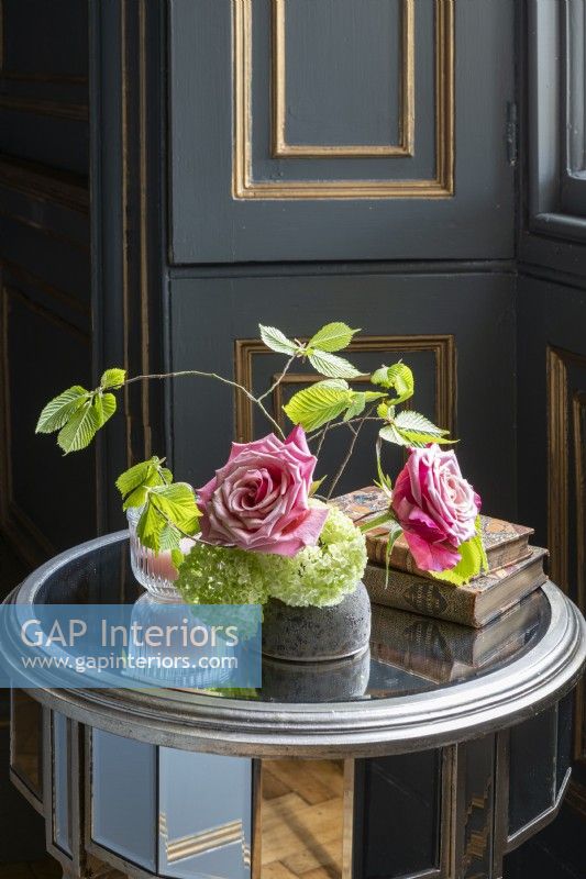 Old roses, beech leaves, and hydrangea in vase in panelled bedroom